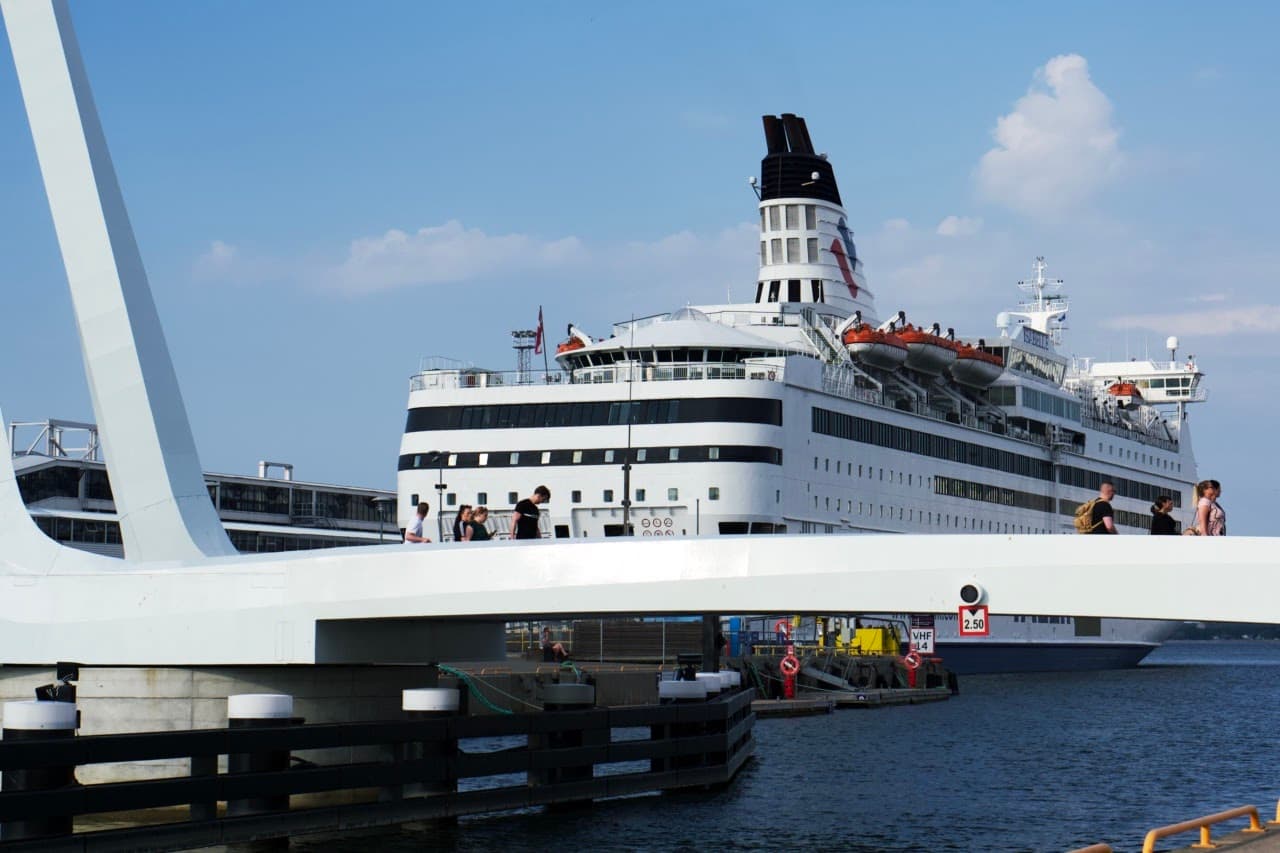 People are crossing Admirali jalakäijate sild (pedestrian bridge) in Tallinn harbour.