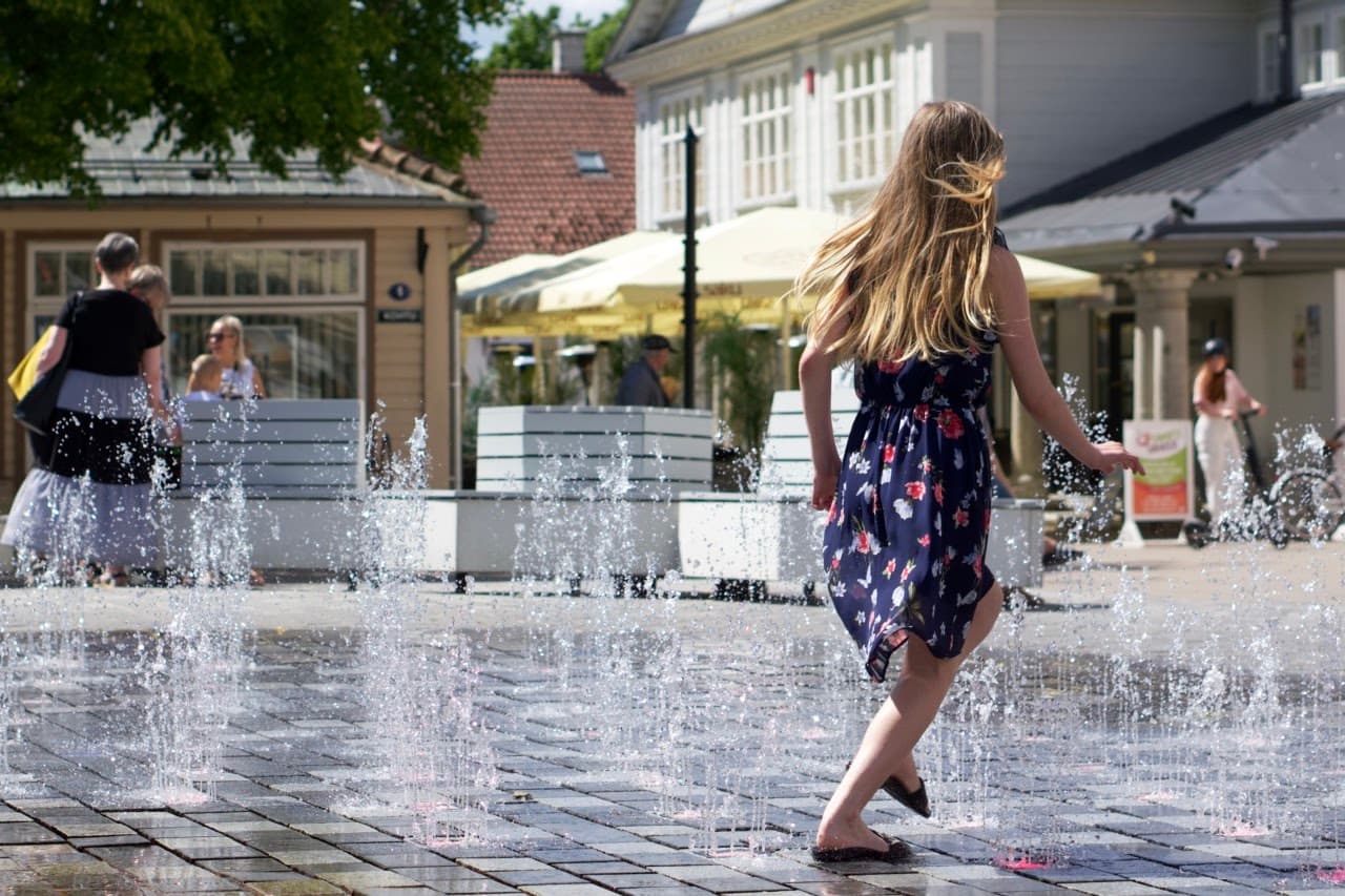 A girl is playing with a water feature at Kuressaare city centre (kesklinn).