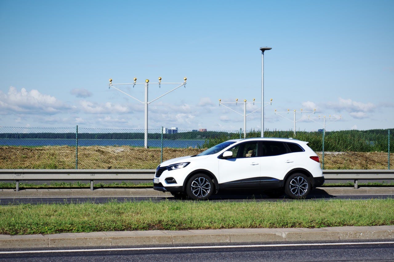 A woman is driving a car on the street at the edge of Tallinn airport's runway.